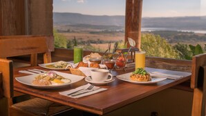 A dining table set with plates of food, drinks, and utensils, overlooking a scenic landscape. - Tapalpa Country Club Hotel (Tapalpa)
