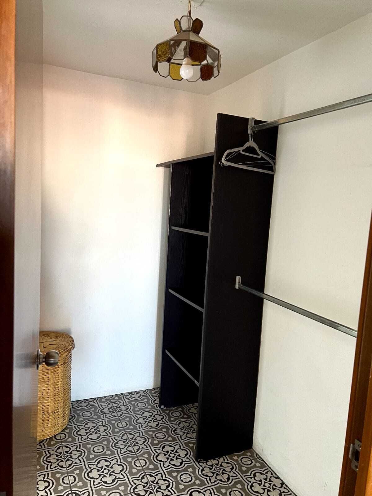 Una habitación pequeña y funcional con un armario negro, una percha y baldosas de piso con diseño.