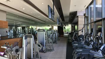 Une salle de sport équipée de divers appareils d’exercice, notamment des tapis de course et des appareils de musculation, disposés en rangées.