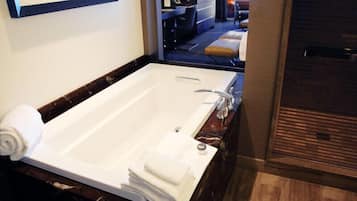 Un baño moderno con una bañera grande, encimera de mármol y suelo de madera.