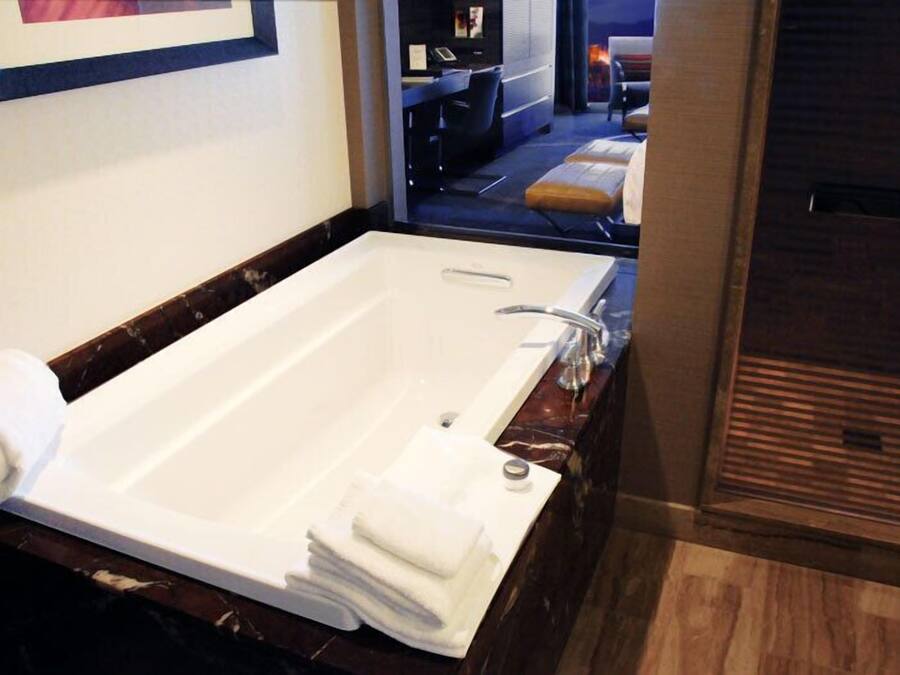 Un baño moderno con una bañera grande, encimera de mármol y suelo de madera.