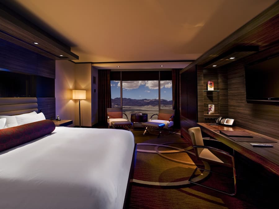 Una habitación de hotel con una cama grande, un escritorio con teléfono y vistas a las montañas.