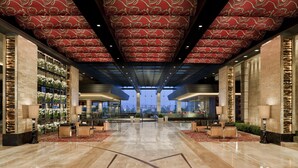 Un hall d’entrée spacieux avec un plafond haut, un espace salon central et une vue sur le paysage urbain grâce à de grandes fenêtres.
