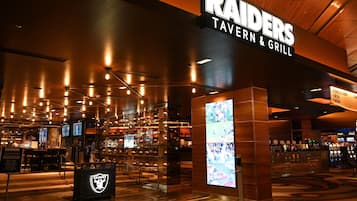 Interior moderno del Raiders Tavern & Grill, con barra, asientos y una gran pantalla digital.