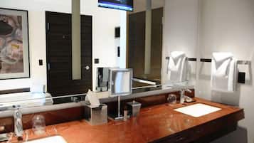 A modern bathroom with a marble sink, a large mirror, and a television mounted on the wall.