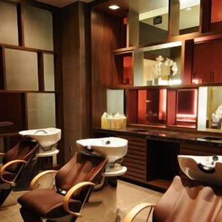 A modern bathroom with a large mirror, a sink, and two chairs.