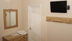 A bathroom with a white door, a wooden dresser with a mirror, a towel, and a flat-screen TV mounted on the wall. - Ayacucho Palace Hotel (Buenos Aires)
