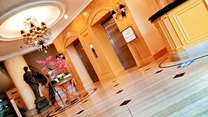 A lobby with a marble floor, a chandelier, a statue, and a sign indicating a 'Millionaire' suite. - The Grand Dame Hotel (Iloilo)