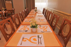 A long dining table with chairs, set for a meal with place settings and a floral centerpiece. - The Grand Dame Hotel (Iloilo)