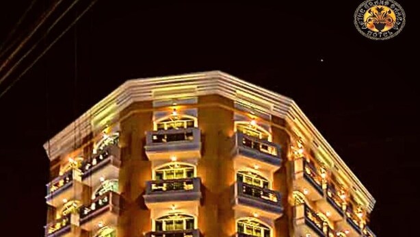 A multi-story hotel with balconies, a central entrance, and a sign indicating a restaurant. - The Grand Dame Hotel (Iloilo)