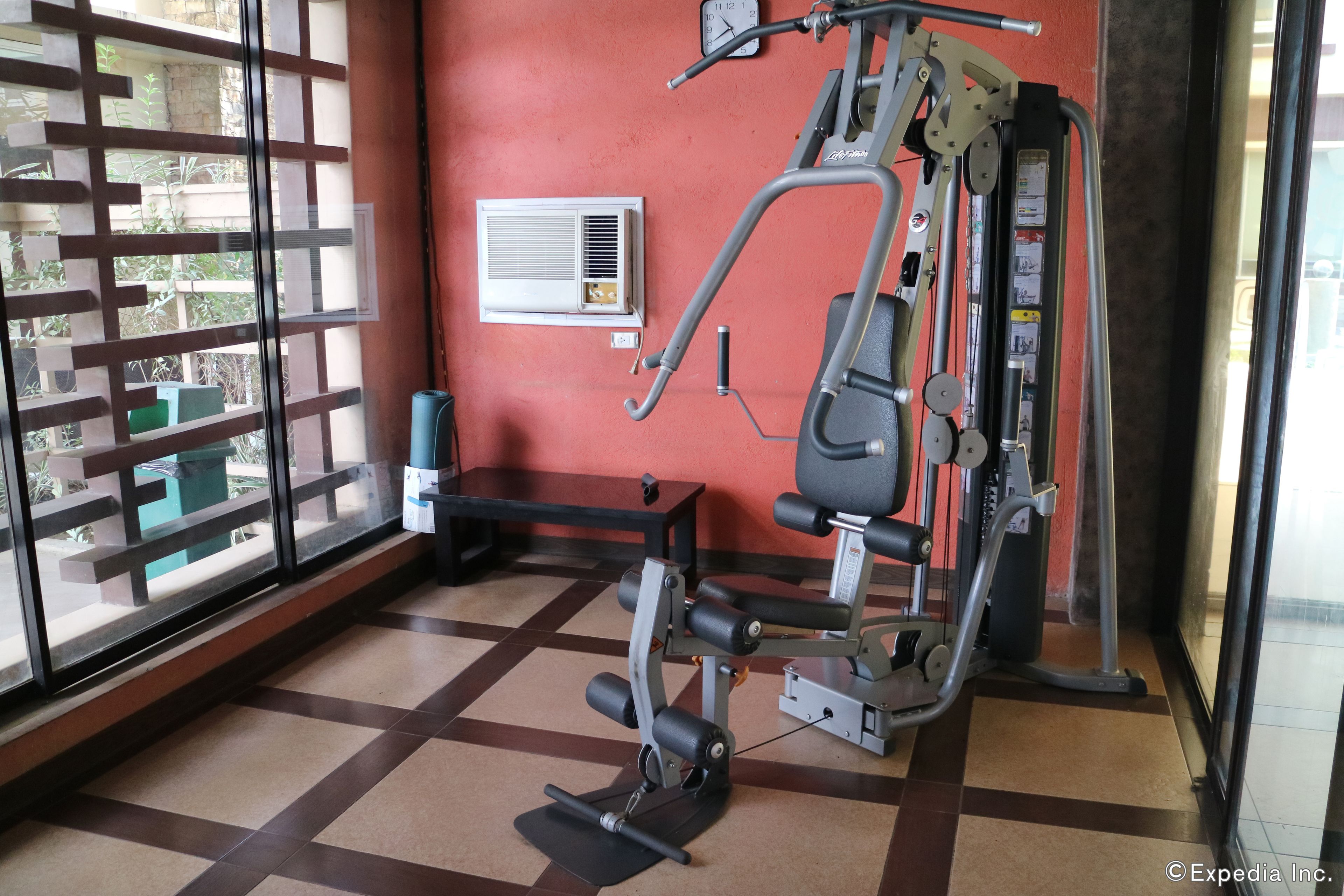 Ein Fitnessraum mit einem Ergometer, einer Bank und einer Wand-Klimaanlage.