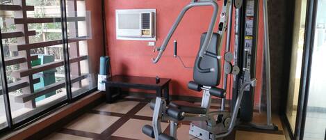 A gym with a stationary bike, a bench, and a wall-mounted air conditioning unit.