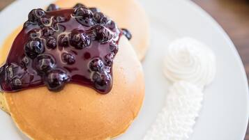 A plate with pancakes topped with blueberry compote and a dollop of whipped cream.