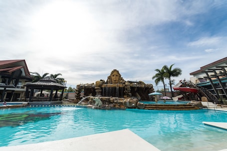 Una piscina al aire libre, sombrillas, sillones reclinables de piscina