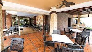 An indoor patio area with tables and chairs, a ceiling fan, and a view of the outside. - MO2 Westown Hotel Iloilo (Iloilo)