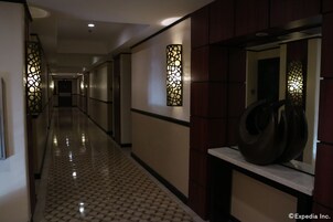 Un pasillo de hotel con piso estampado, apliques de pared y una escultura moderna sobre una consola.