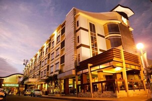 A multi-story hotel with a modern design, featuring a prominent entrance with a covered area and a visible sign for the hotel.