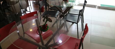 Un comedor con mesas redondas de vidrio y sillas rojas.