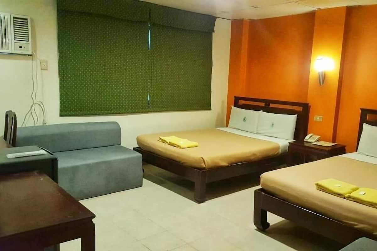 A hotel room with two beds, a sofa, and a desk.