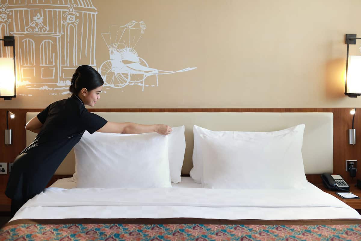 Une chambre d’hôtel avec un lit bien fait, une couvre-lit à motifs et une fresque murale.