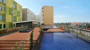A rooftop pool area with lounge chairs and a view of the cityscape. - Swiss-Belhotel Airport Jakarta (Tangerang)