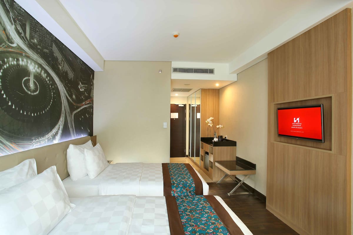 Une chambre d’hôtel avec un grand lit, une télévision, une œuvre d’art murale et une petite kitchenette.