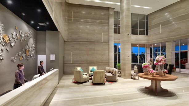 A spacious lobby with a reception desk, seating area, and a large window providing a view of the outside. - Swiss-Belhotel Airport Jakarta (Tangerang)