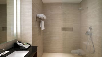 Un baño moderno con un espejo grande, un lavamanos, una ducha y un perchero para toallas.