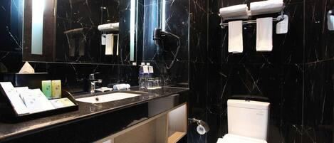 A modern bathroom with a black marble sink, a mirror, a toilet, and a towel rack.