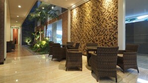 Eine Lobby mit modernem Design, inklusive einer Steinwand, Korbmöbeln und einem kleinen Innenhofgarten.