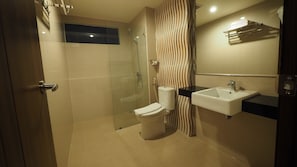 Un baño moderno con cabina de ducha de vidrio, inodoro, lavabo y toallero.