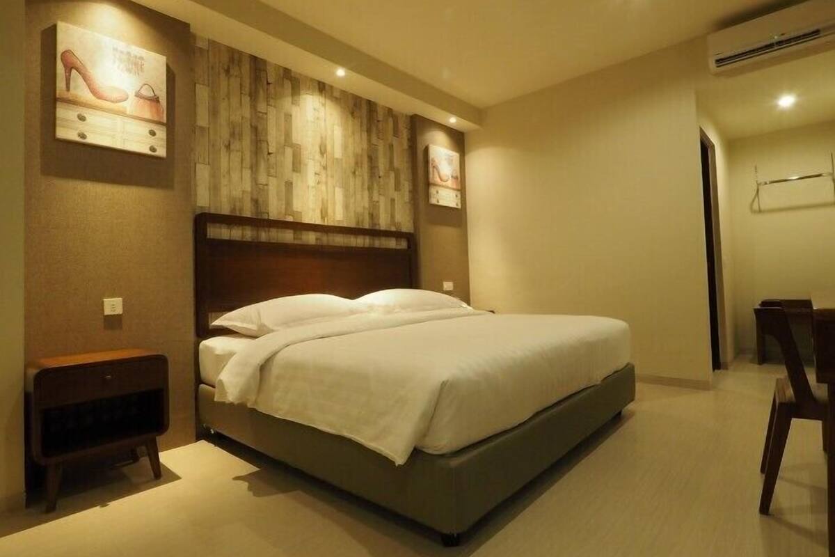 Un dormitorio moderno con una cama grande, cabecera de madera y una obra de arte colgada en la pared.