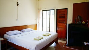 A hotel room with a single bed, a wooden headboard, a window with curtains, a wooden door, and a desk with a chair. - Safe House Court (Chiang Mai)
