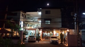 A two-story building with a well-lit entrance and parked cars. - Safe House Court (Chiang Mai)