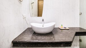 Un baño con un lavabo blanco, un espejo y un secador de pelo.