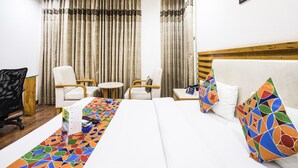 Una habitación de hotel con una cama, dos sillones, una mesita y un escritorio con silla.