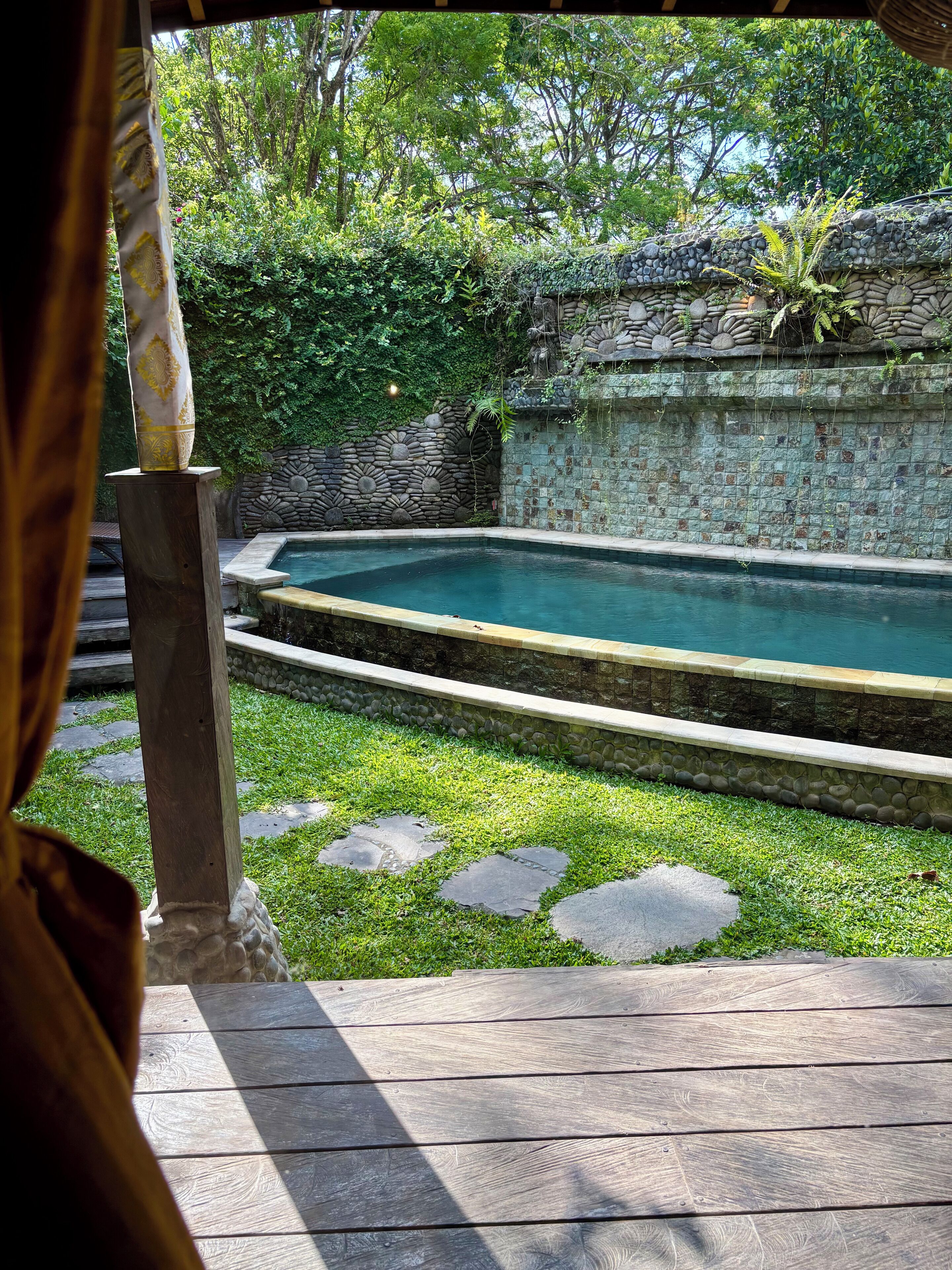 A pool area with stone walls and a wooden deck.