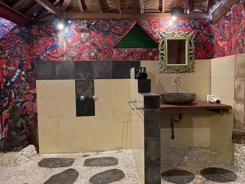 A bathroom with a shower, a sink, and a decorative mirror.