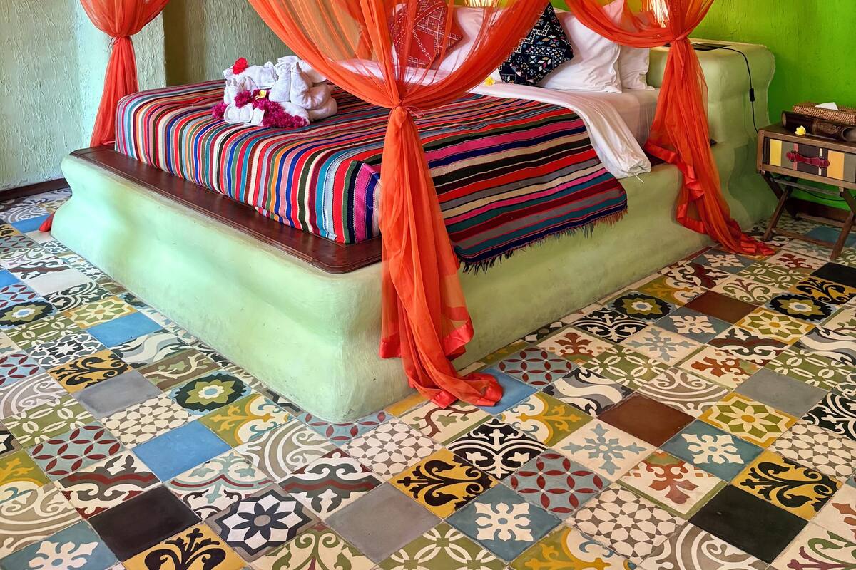 A room with a bed under a red canopy, a green wall, and a tiled floor.