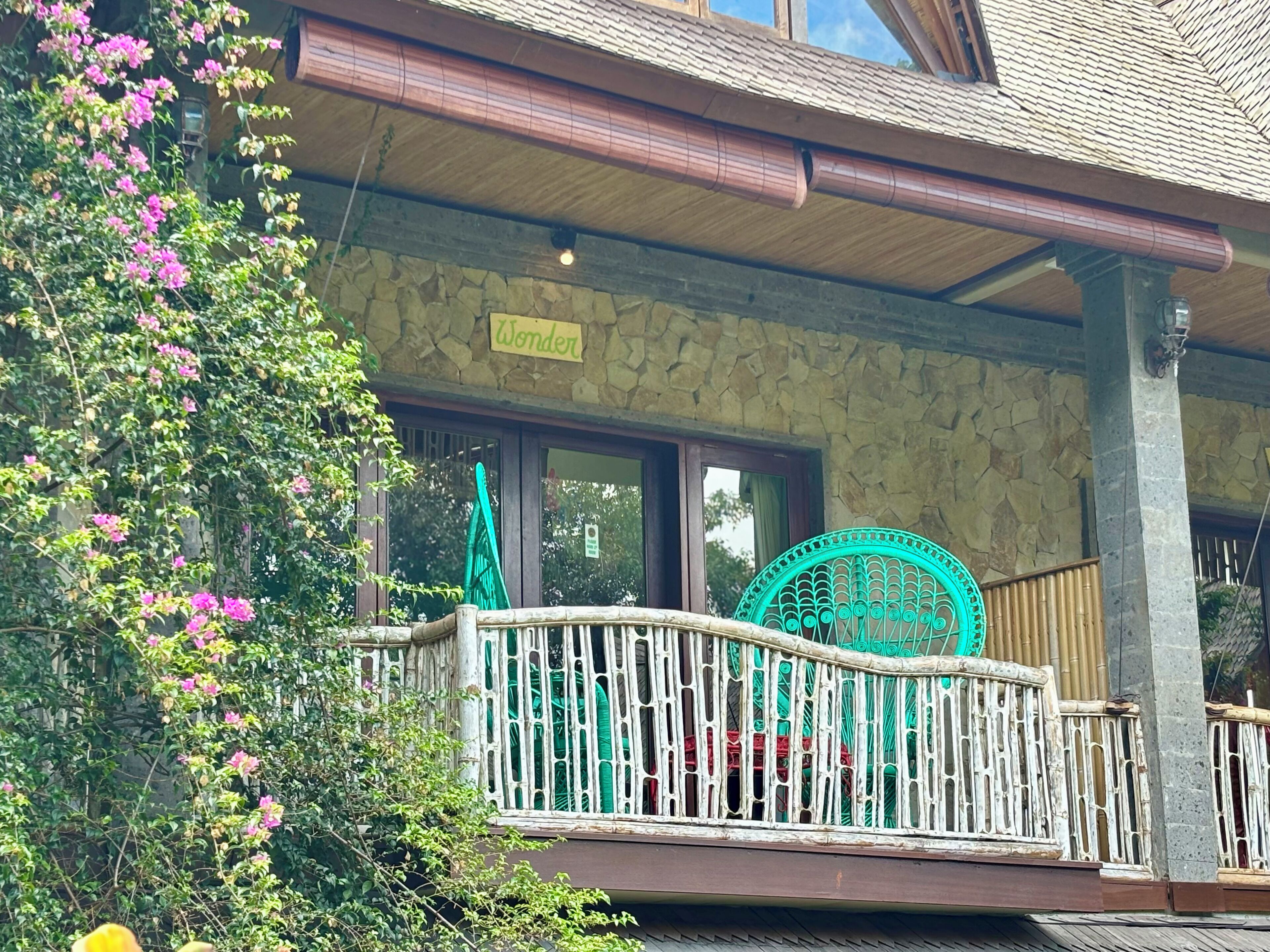 A building with a stone facade, a balcony with a white railing, and a sign that reads "Wonder".