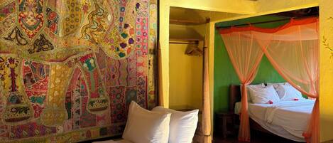 A room with a bed, a canopy bed, a colorful tapestry, and a patterned floor.