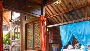 A rustic wooden room with a bed under a blue canopy, a wooden table, and a chair. - Bali Bohemia (Ubud)