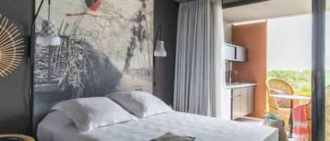 A bedroom with a bed, a map mural, a balcony with a table and chairs, and a view of the outdoors.