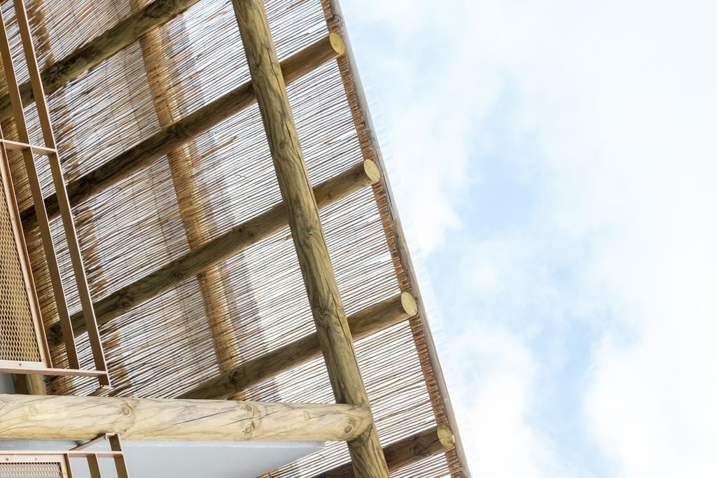 A wooden structure with horizontal beams and a mesh-like pattern, likely part of a building's exterior.