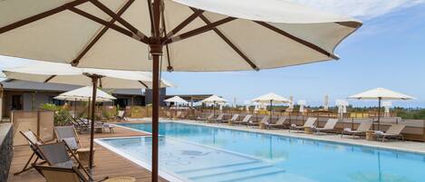 A pool area with lounge chairs and umbrellas.
