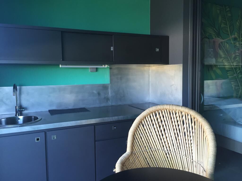 A kitchen with dark cabinets, a stainless steel sink, and a wicker chair.