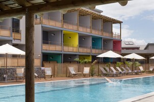 Una piscina al aire libre, sombrillas, sillones reclinables de piscina
