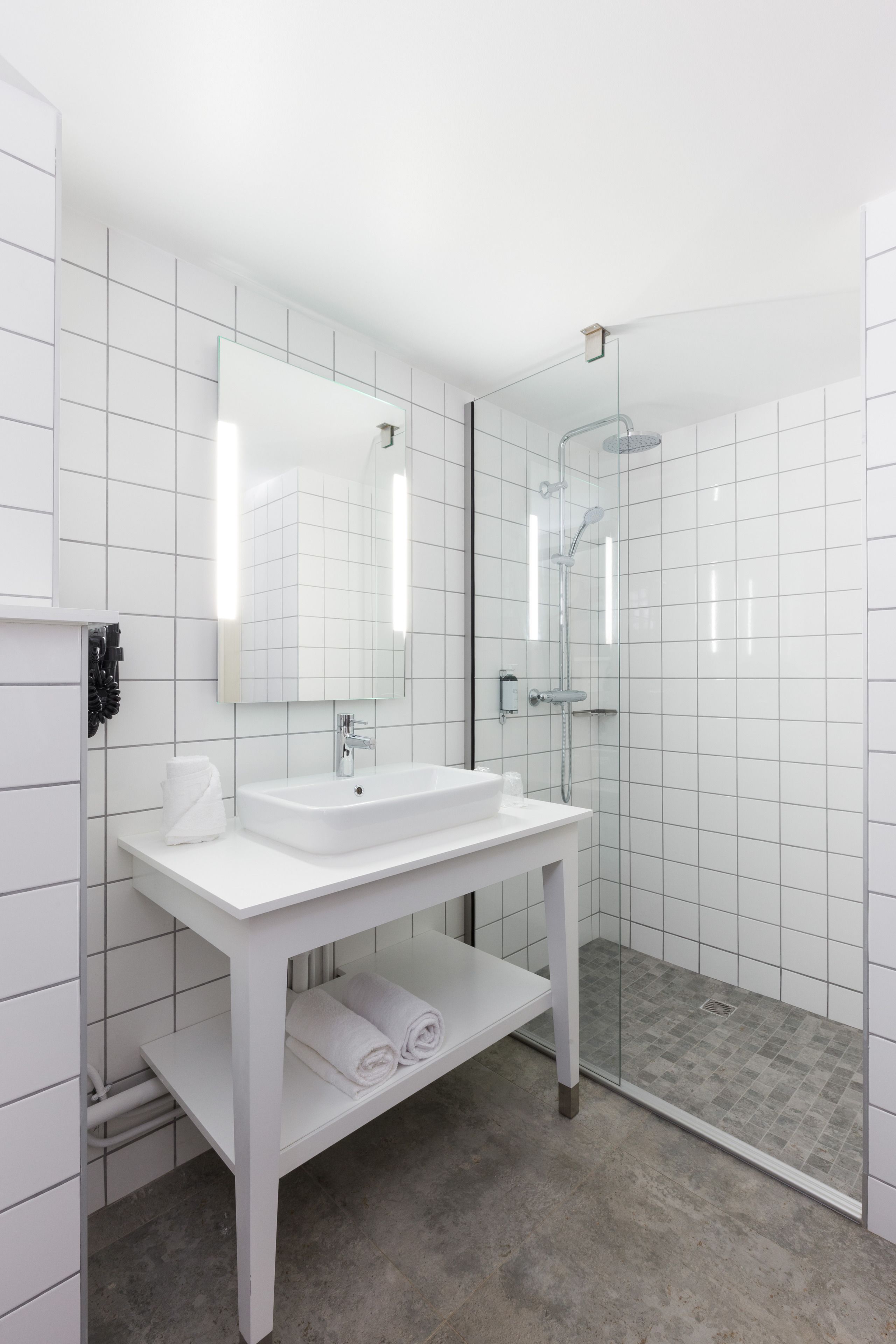 A modern bathroom with a white vanity, a large mirror, and a glass-enclosed shower.