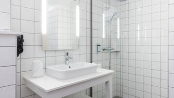 A modern bathroom with a white vanity, a large mirror, and a glass-enclosed shower.