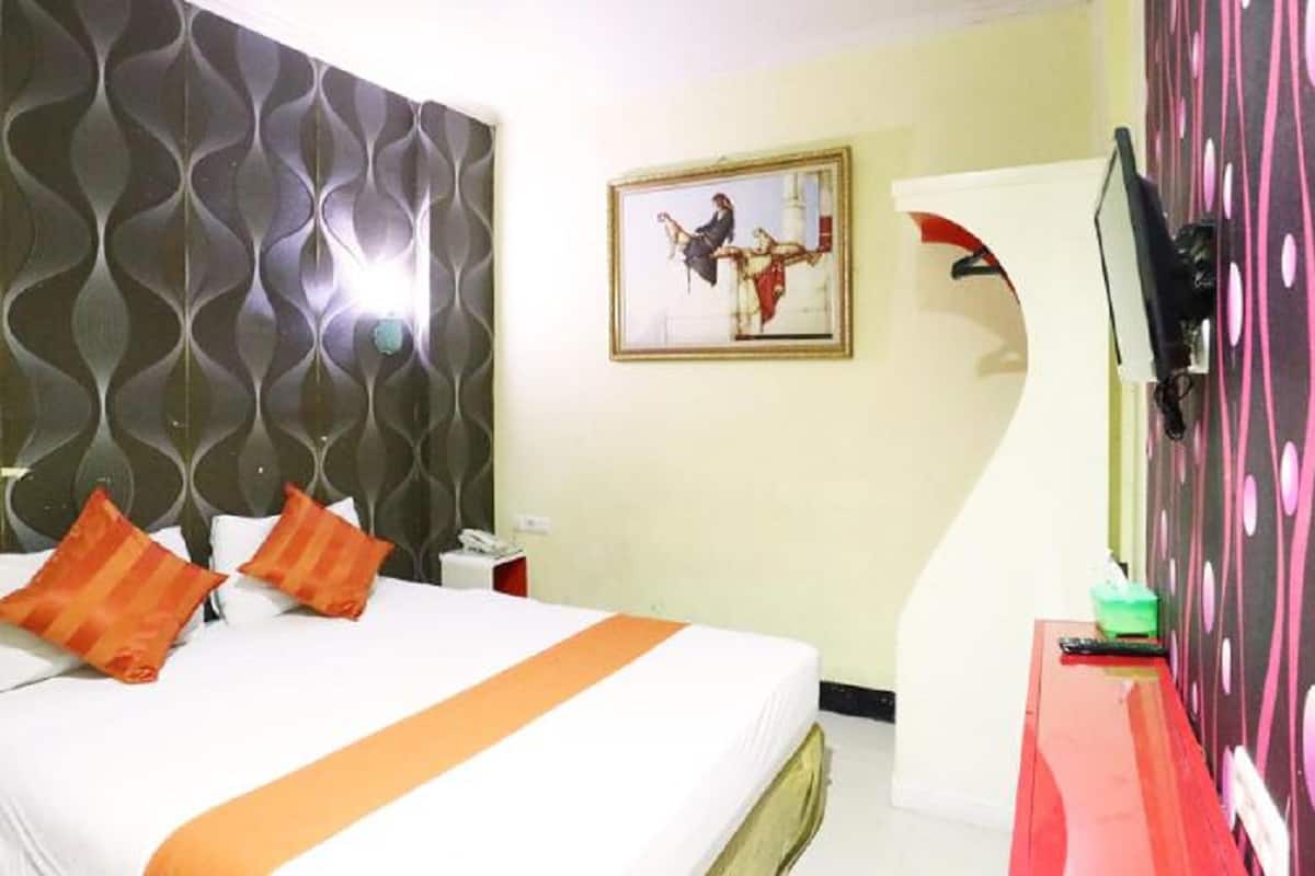 Une chambre d’hôtel avec un lit, un tableau, une télévision et un bureau.